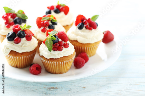 Tasty cupcakes with berries on white wooden table