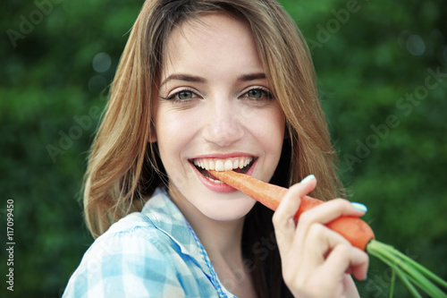 Beautiful girl eating carrot, closeup