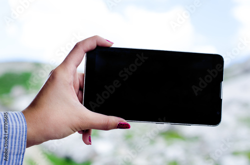 woman´s hands taking a photo with smartphone. Natural background. View on a mobile phone. Black screen. technology photo