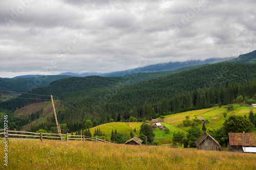 Rural houses in Carpathian mountains. Cloudy summer landscape, Ukraine, Europe.
