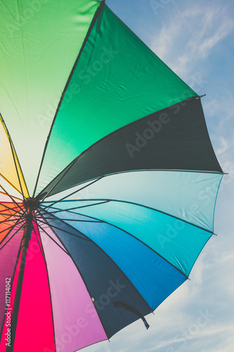 open colorful rainbow umbrella on blue sky background  vintage look