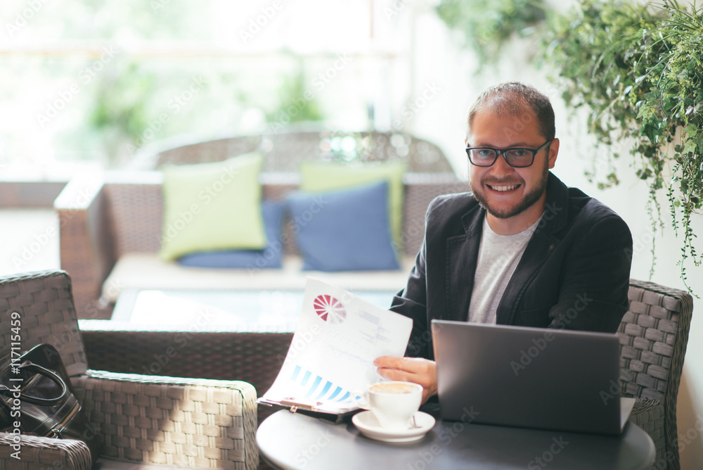 Obraz premium young aspiring businessman working at a laptop in a cafe