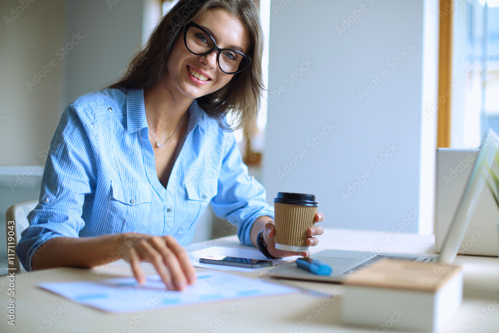 Young woman sitting at office table with laptop Young woman sitting at office table with laptop