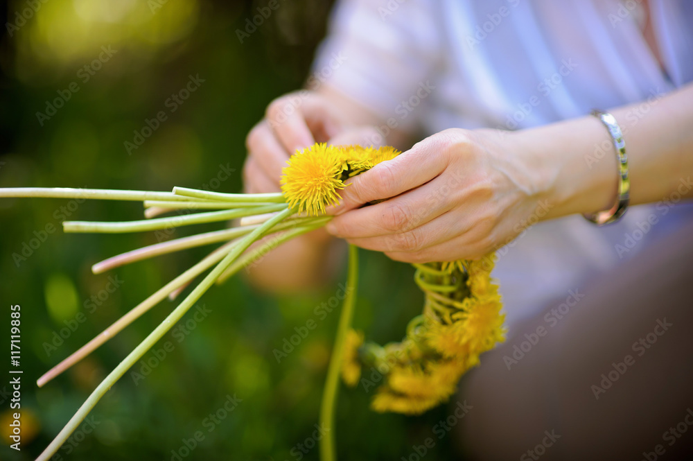 Fototapeta premium wreath of yellow dandelions in hands