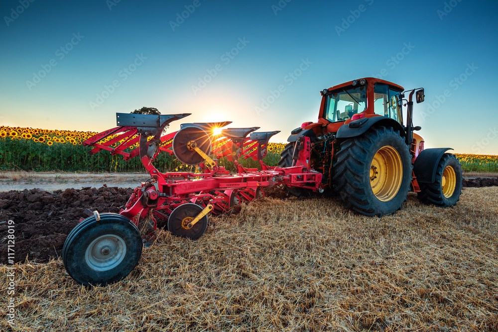 Fototapeta Farmer in tractor preparing land with cultivator