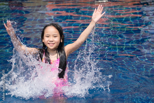 Asia kid girl at the pool and smiling happy