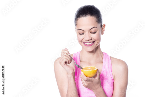 Smiling young woman eating an orange