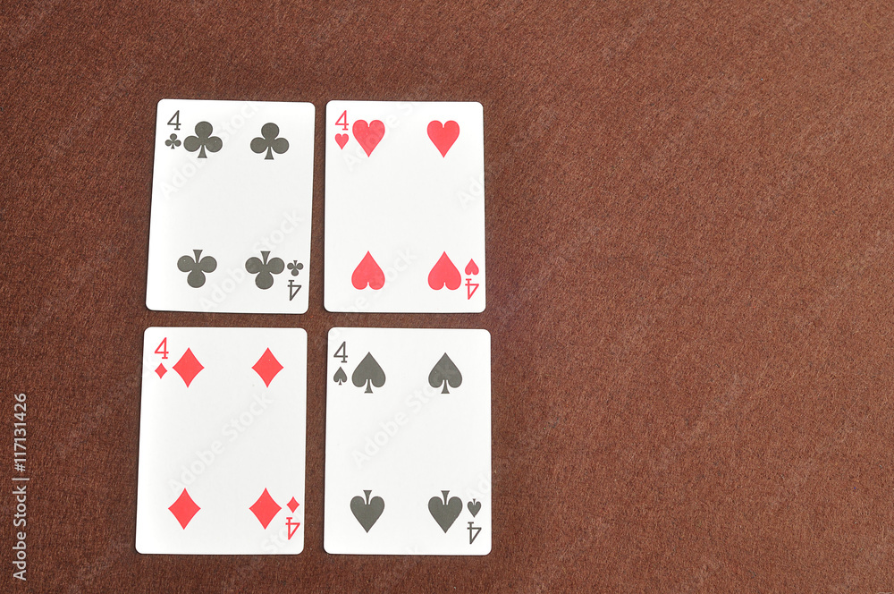 The different suit of the number 4 cards in a deck of cards displayed on a brown background