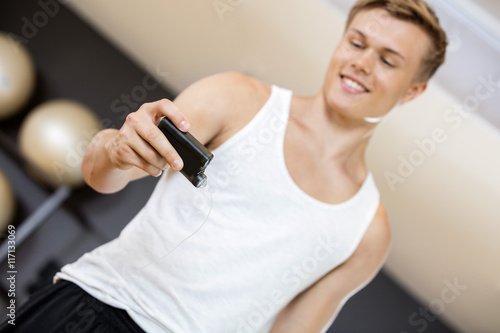 Young Man Holding Glucose Monitor In Gym