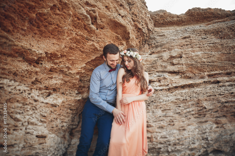 Romantic loving couple walking on the beach with rocks and stones Romantic loving couple walking on the beach with rocks and stones