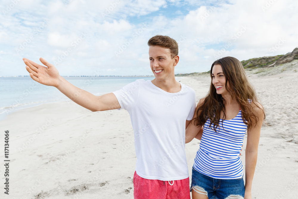 Happy young man and woman couple together walking on a beach