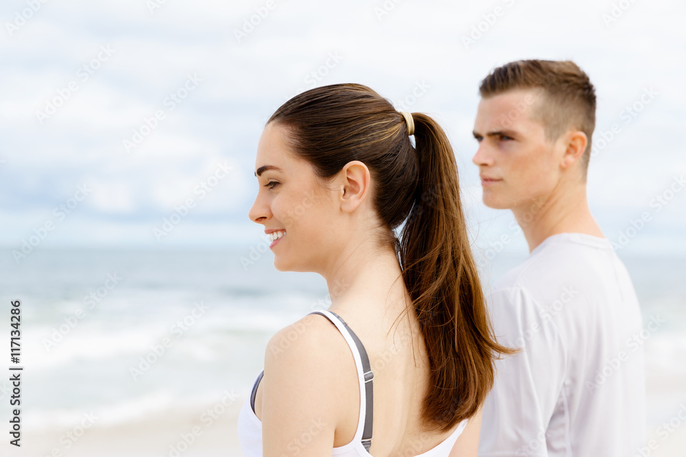 Young couple looking thoughtful while standing next to each other on beach Young couple looking thoughtful while standing next to each other on beach