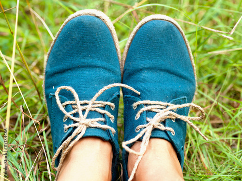 female legs in dark blue sneakers on a background of green grass