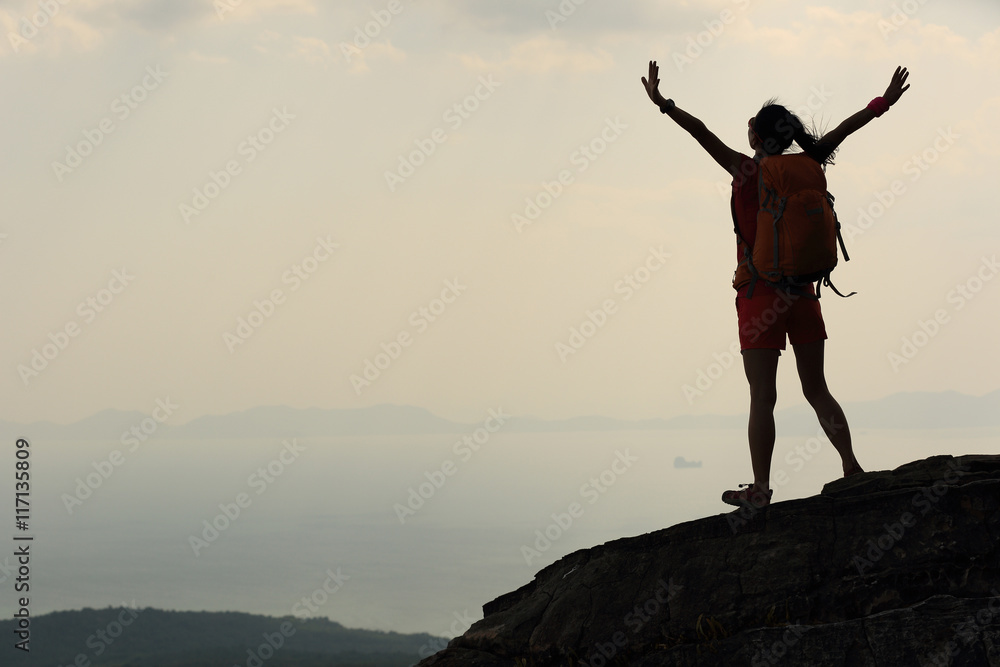cheering young asian woman open arms on mountain peak cliff