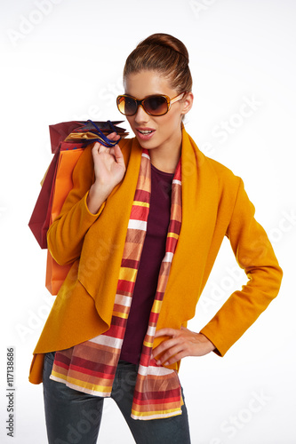 Woman wearing autumn overcoat and scarf holding shopping bag.
