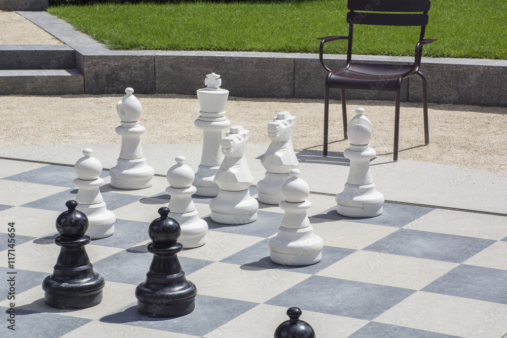 Black and white chessmen on the street chessboard in the daylight
