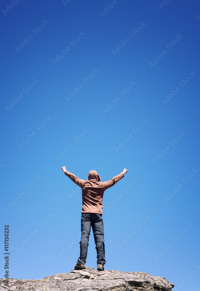 Man standing on the top of the mountain over blue sky Man standing on the top of the mountain over blue sky