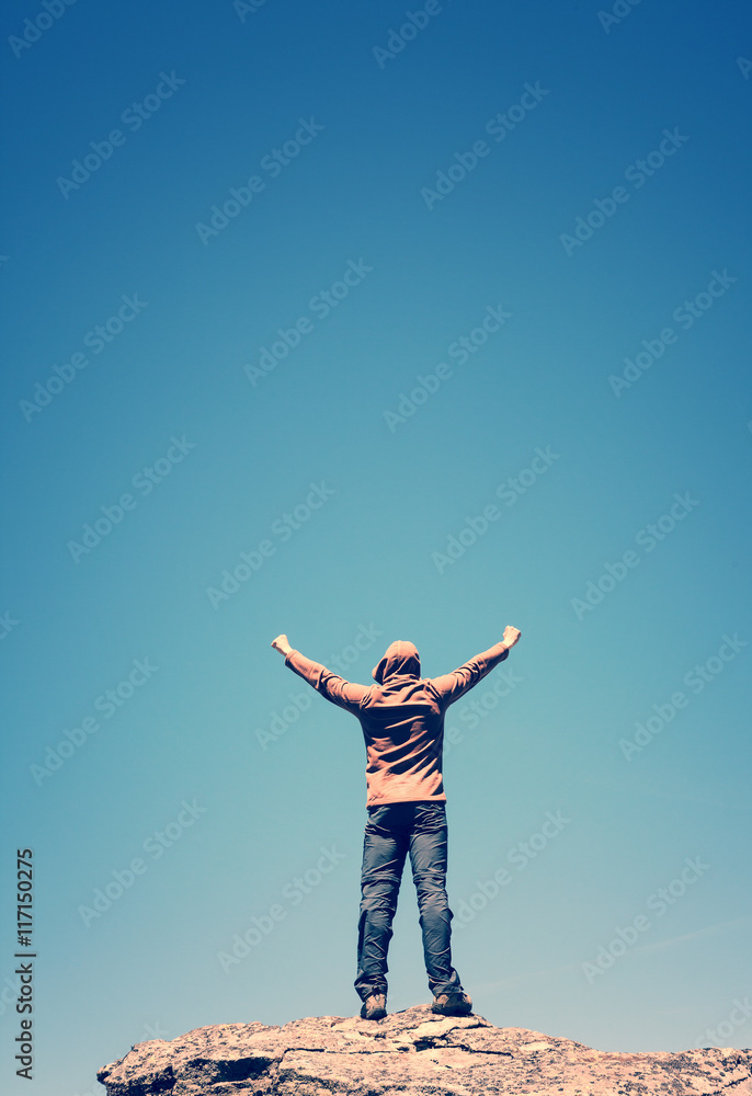Man standing on the top of the mountain over blue sky Man standing on the top of the mountain over blue sky