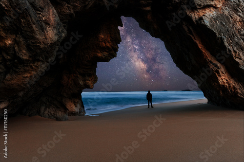 Lonely man at the rocky arch watching milky way