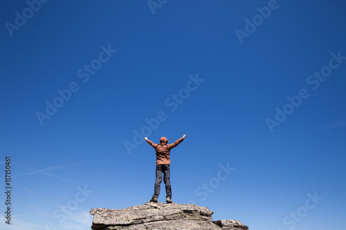 Man standing on the top of the mountain over blue sky