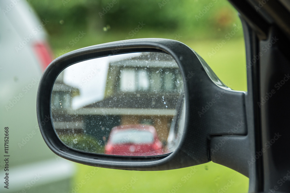 Car side rear view mirror with house reflection in UK residential area
