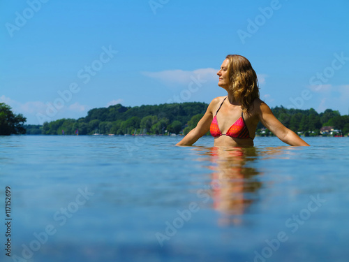 Frau  50 Jahre alt  genie  t mit geschlossenen Augen das Enspannen im See im Sommerurlaub 