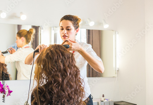 Fotografie Professional hairdresser styling woman curly hair.