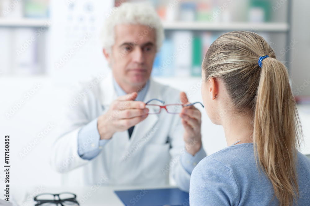 Obraz premium Optician giving glasses to the patient