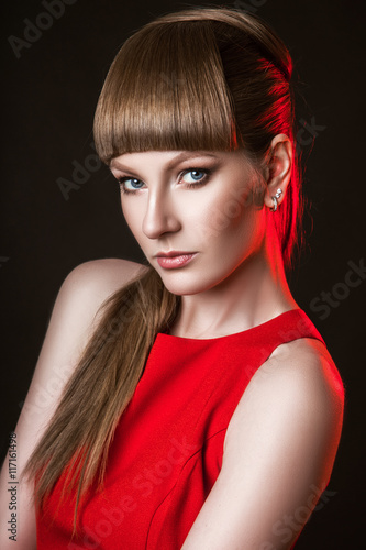 beautiful woman model posing in simple elegant red dress in the studio on black background
