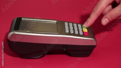 Hand dialing pin code on pin pad of pos terminal on red background