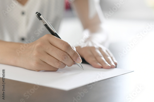 Closeup of woman's hand writing on paper with pen photo