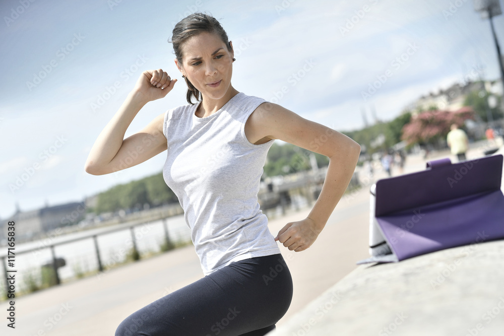 Fitness girl in town exercising with virtual coach Fitness girl in town exercising with virtual coach