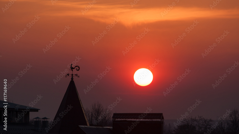 Fototapeta premium Magnificent sunset over the rooftops. wind indicator.sun.