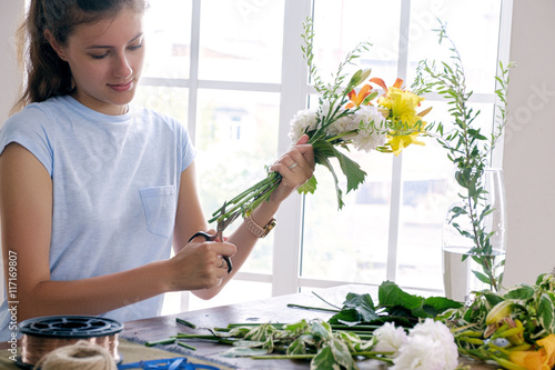 Slika na platnu Girl cutting flowers at table