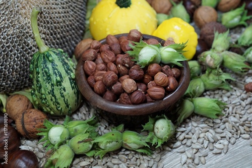 Shelled hazelnuts in a bowl and green hazelnuts on the background of sunflower seeds - selective focus