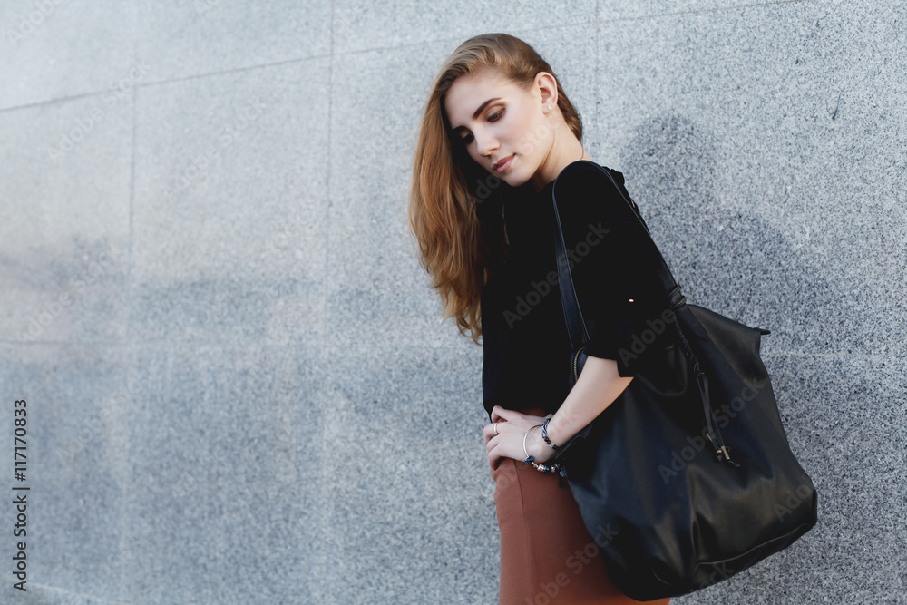 Beautiful woman wearing black blouse, brown pencil skirt and high heels shoes with leather bag posing at the evening city street. Vogue, female model Beautiful woman wearing black blouse, brown pencil skirt and high heels shoes with leather bag posing at the evening city street. Vogue, female model