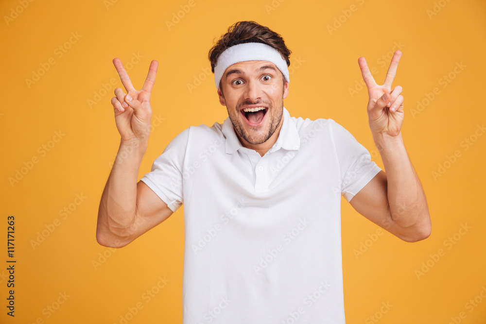 Happy excited young male athlete shouting and showing victory sign