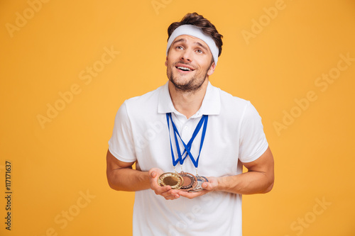 Portrait of smiling young spotrsman with three medals photo