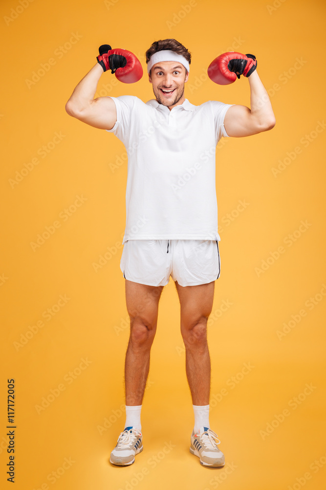 Cheerful man boxer in red gloves smiling and showing biceps Cheerful man boxer in red gloves smiling and showing biceps
