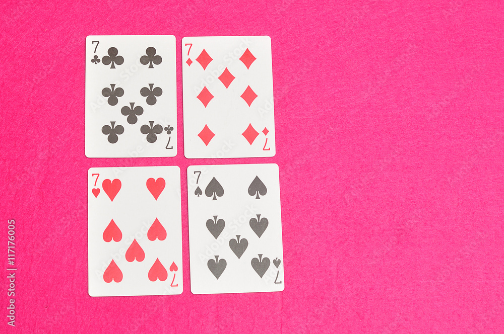 The different suit of the number 7 cards in a deck of cards displayed on a pink background The different suit of the number 7 cards in a deck of cards displayed on a pink background