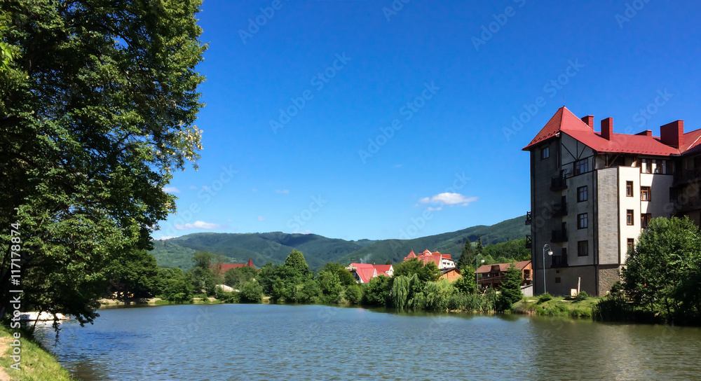 Landscape building on the lake a background of forested mountains and blue sky, outdoor travel backdrop Ukraine Zakarpattia Polyana village