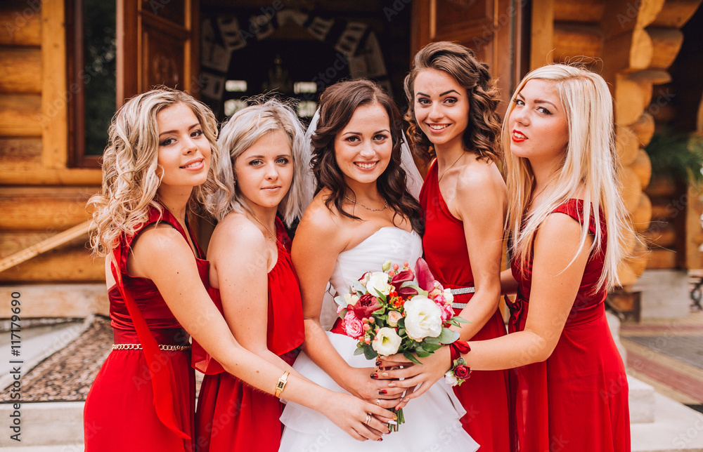Bride with bridesmaids on the park on the wedding day. Bridesmaids near church.