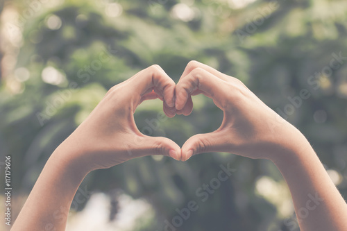 Hand on heart-shaped bokeh background blurred, natural tones vintage style. Show the world you love Love Family between two people.