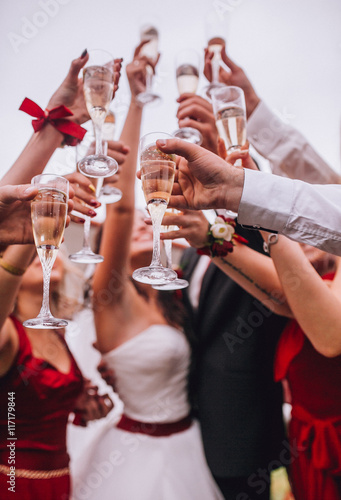 Guests clink glasses on wedding celebration. Lot og glasses with champagne in hand og yung people.