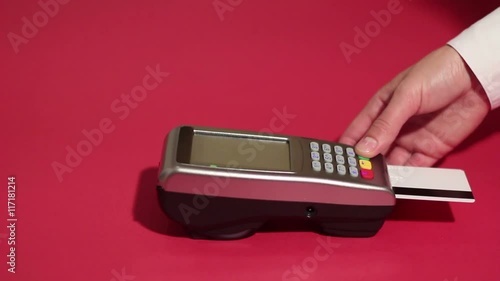 Inserting credit card into card machine and dialing pin code on red background