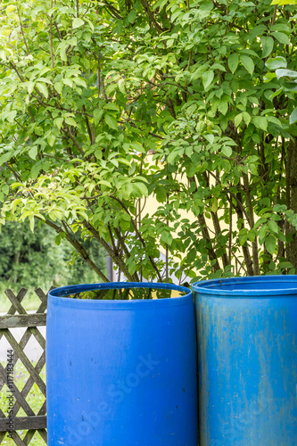 blue rain barrels gathering water in garden