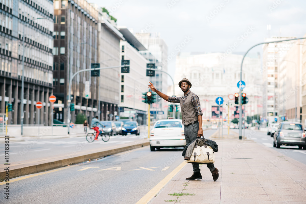 Young man waving hand for taxi on street