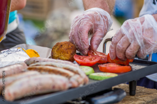 Valokuva Chef roasting sausages and vegetables on the grill