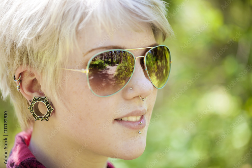 A forest path reflected in the glasses of a hip young woman. A forest path reflected in the glasses of a hip young woman.