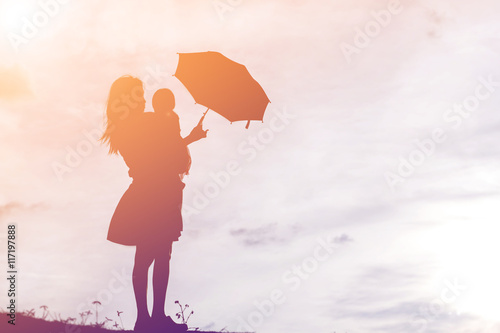 Mother holding baby walking on the sunset background.